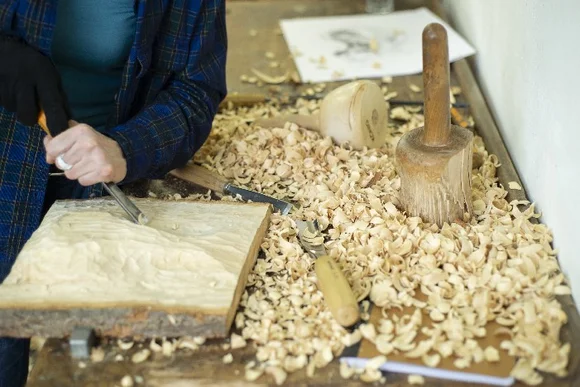 Person schnitzt mit Stechbeitel in Holz